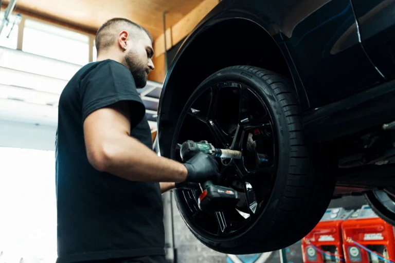 Mécanicien changeant un pneu sur une voiture surélevée en atelier